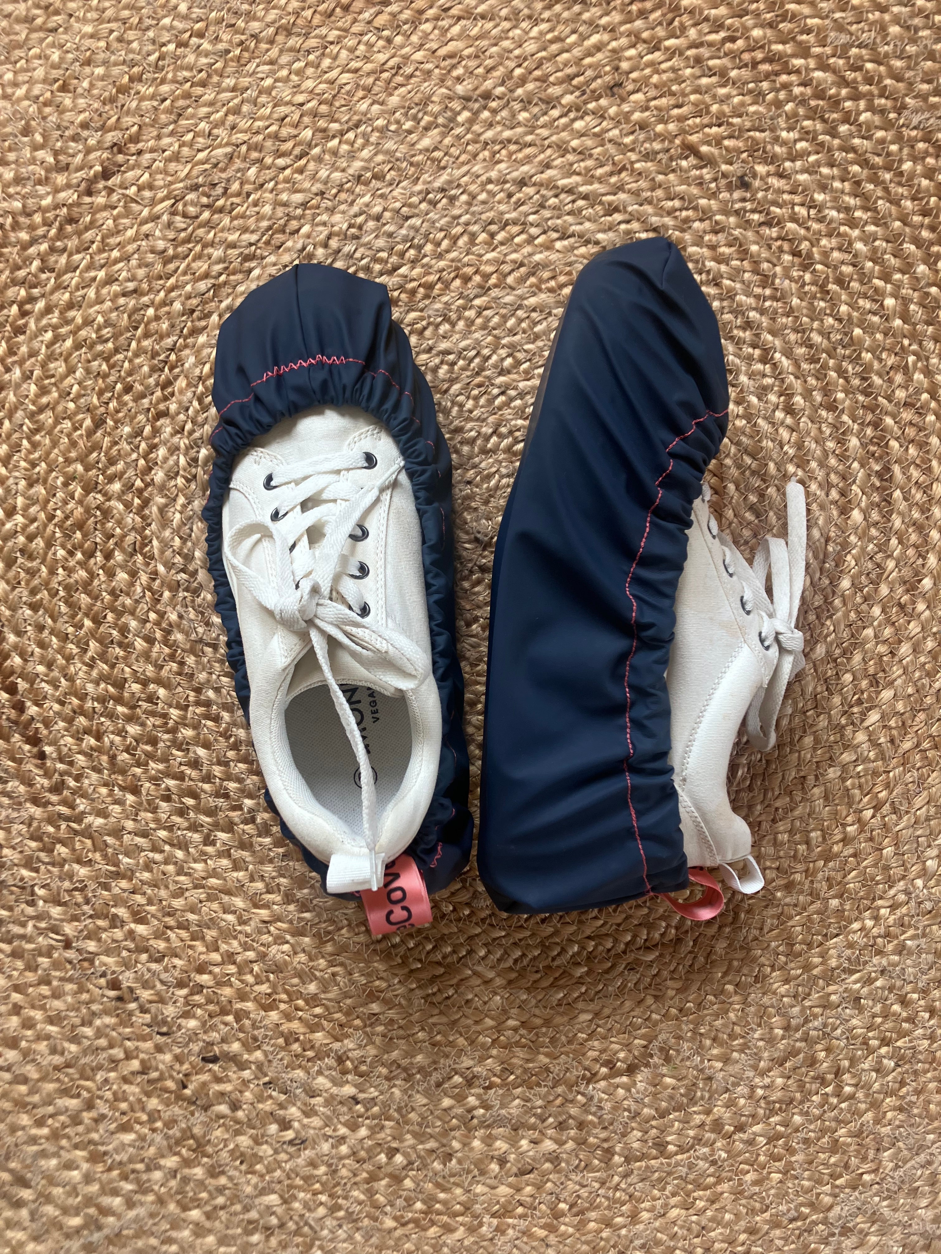 Pair of baby shoes with navy covers on a beige carpet