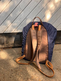 Backpack with brown leather accents on a concrete surface