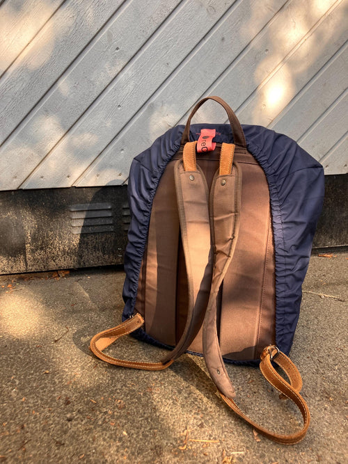 Backpack with brown leather accents on a concrete surface